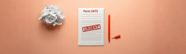 Libreta con el título «Form 5472» y un sello rojo «URGENT», junto a un lápiz y una hoja de papel arrugada